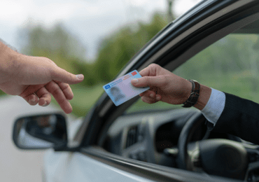 man offering his driver's license to the police after being stopped